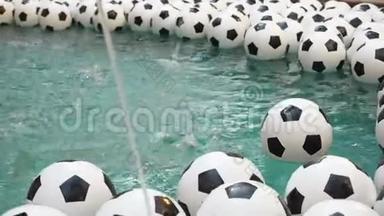 许多黑白足球背景。 足球球在纯净水中游泳。 一球落入水中